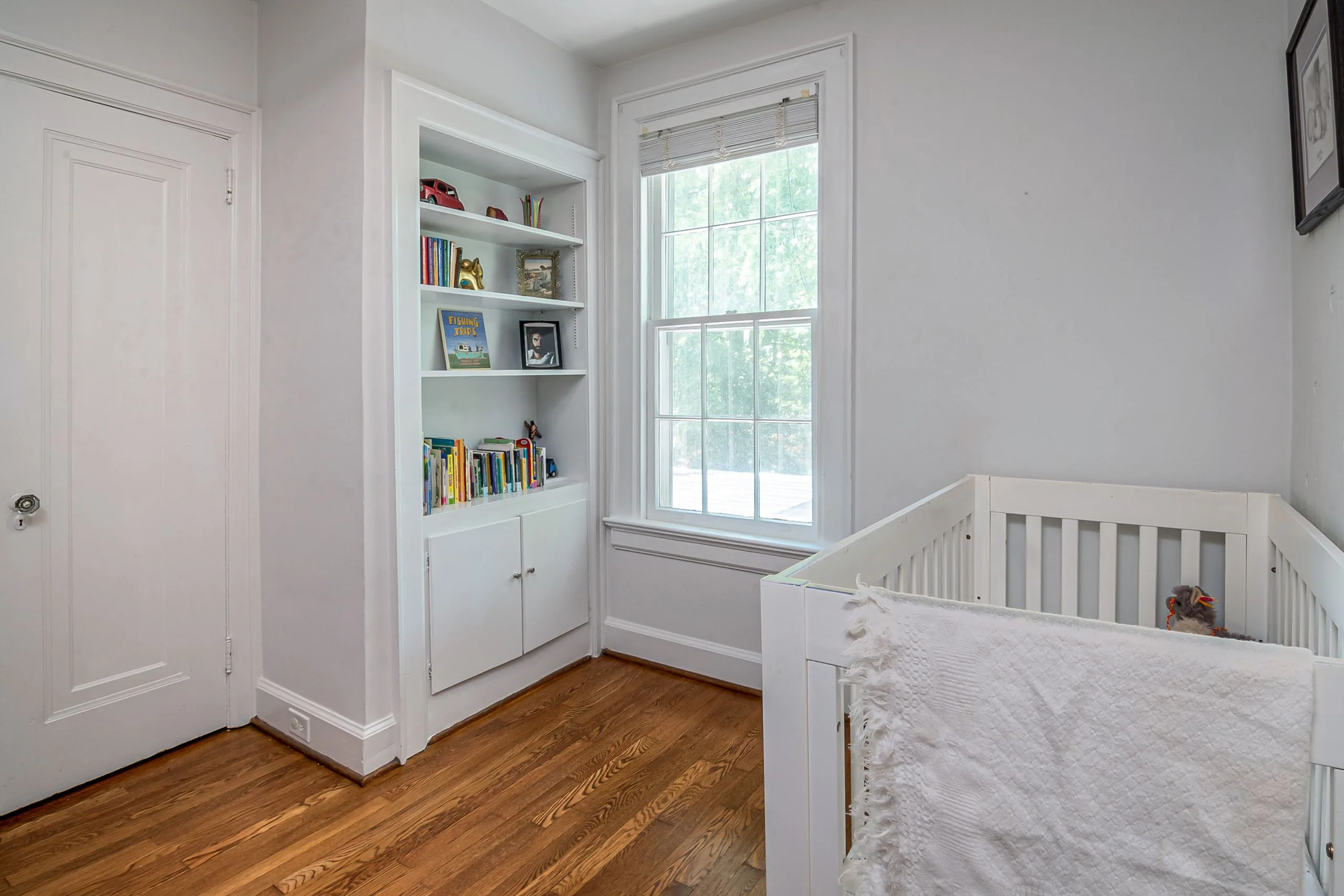 Bibliothèque enfant basse en bois clair dans une chambre, livres rangés face visible et bacs de jouets